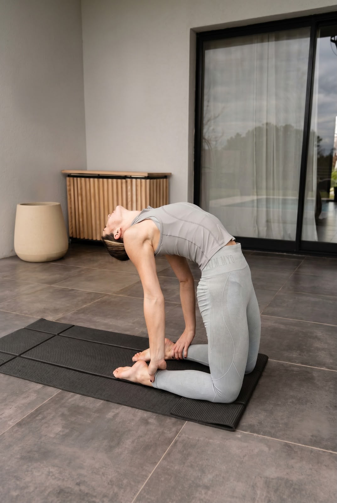 Woman in camel pose on a black Foldy Mat on a terrace