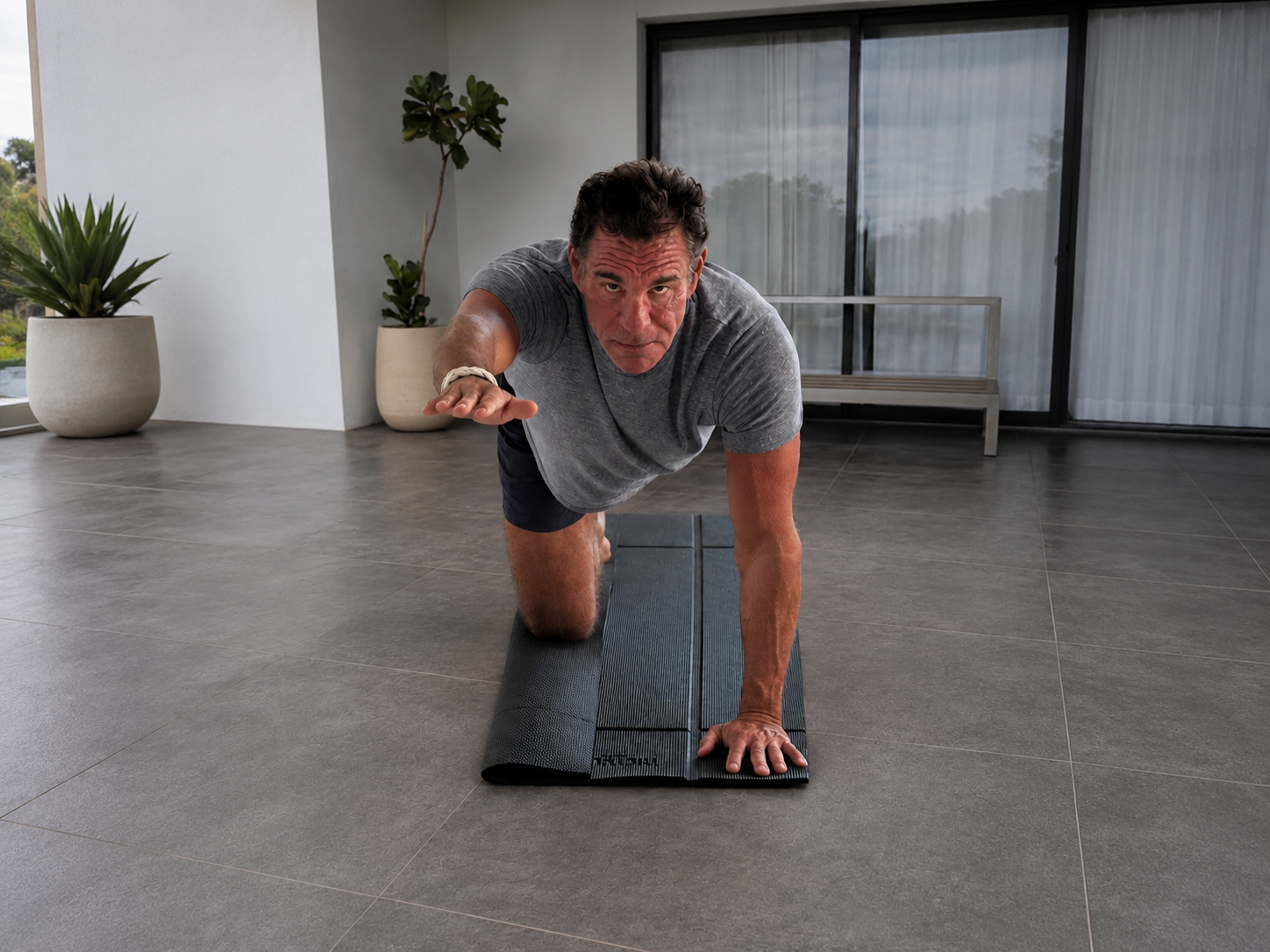 Man in a kneeling balance pose reaching forward on a Foldy Mat